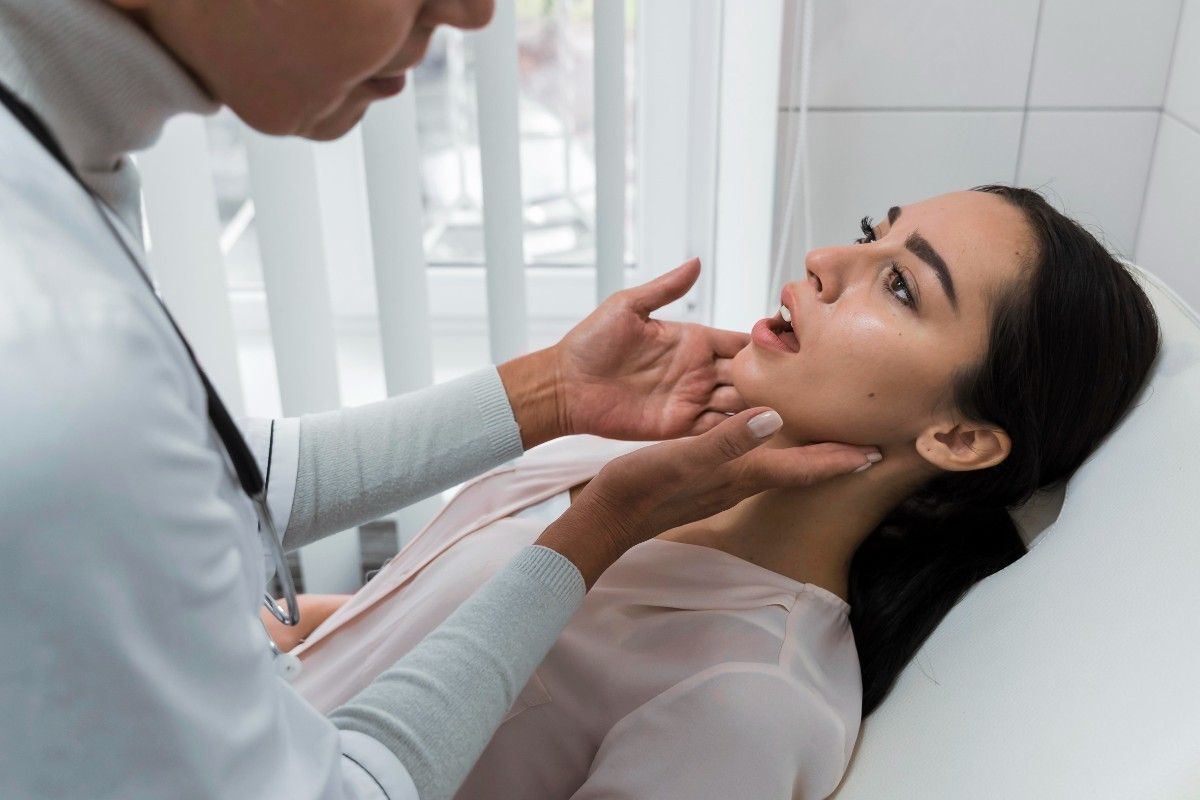 Dental Implants vs. Bridges Dentist examining a woman’s jaw during a dental checkup.