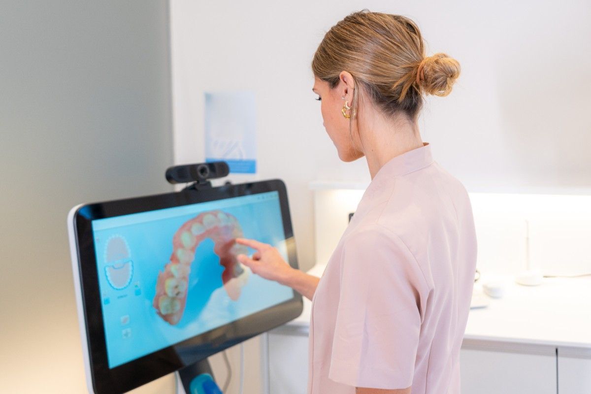 Same-Day Dental Crowns Dentist reviewing a 3D digital scan of teeth on a touchscreen monitor in a modern dental clinic