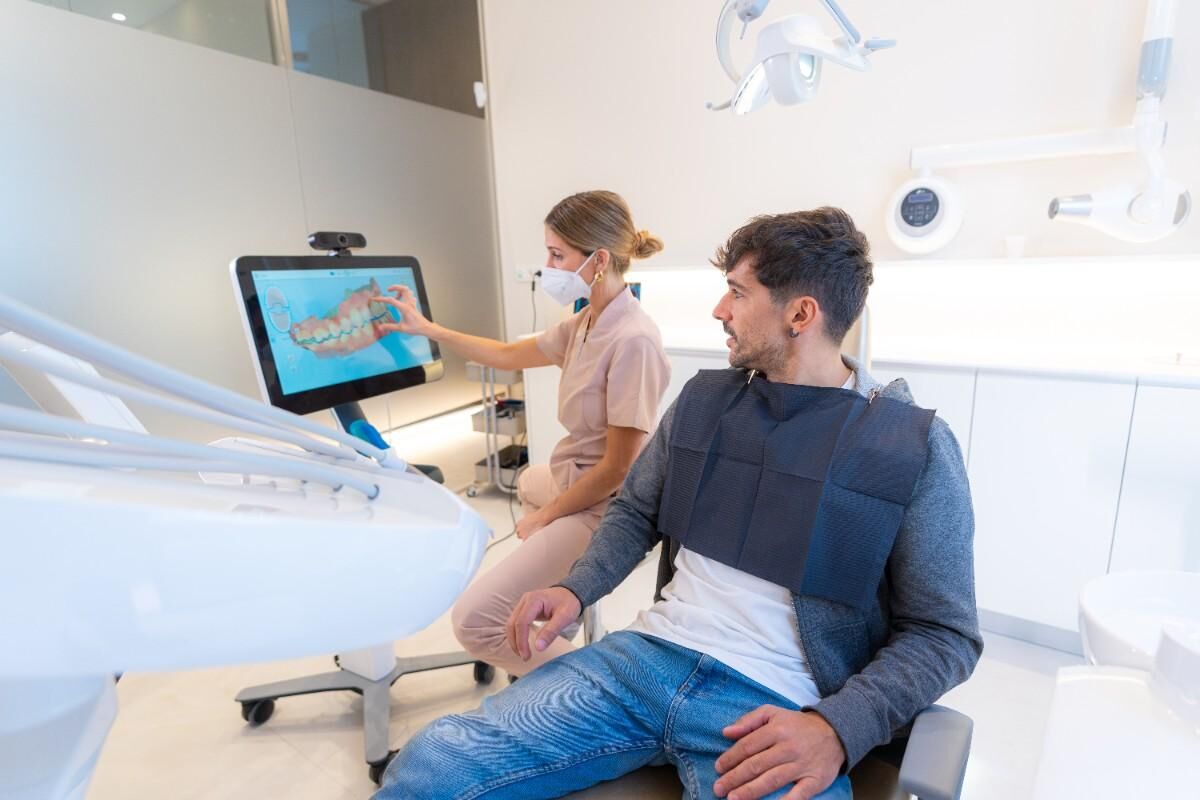 clear-aligner-smile-transformation Dentist showing digital smile design to patient in modern clinic