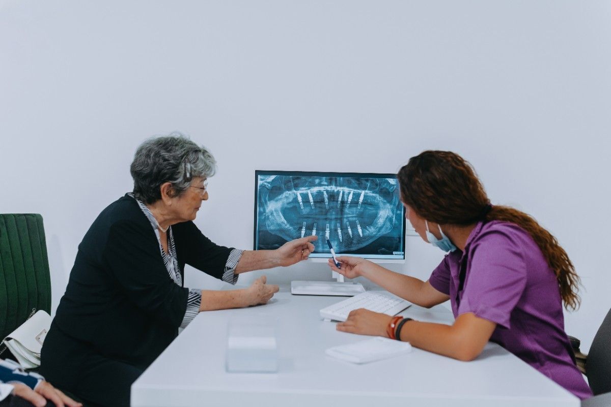 lasting-cosmetic-smile-results Dentist reviewing dental X-ray with senior patient during consultation