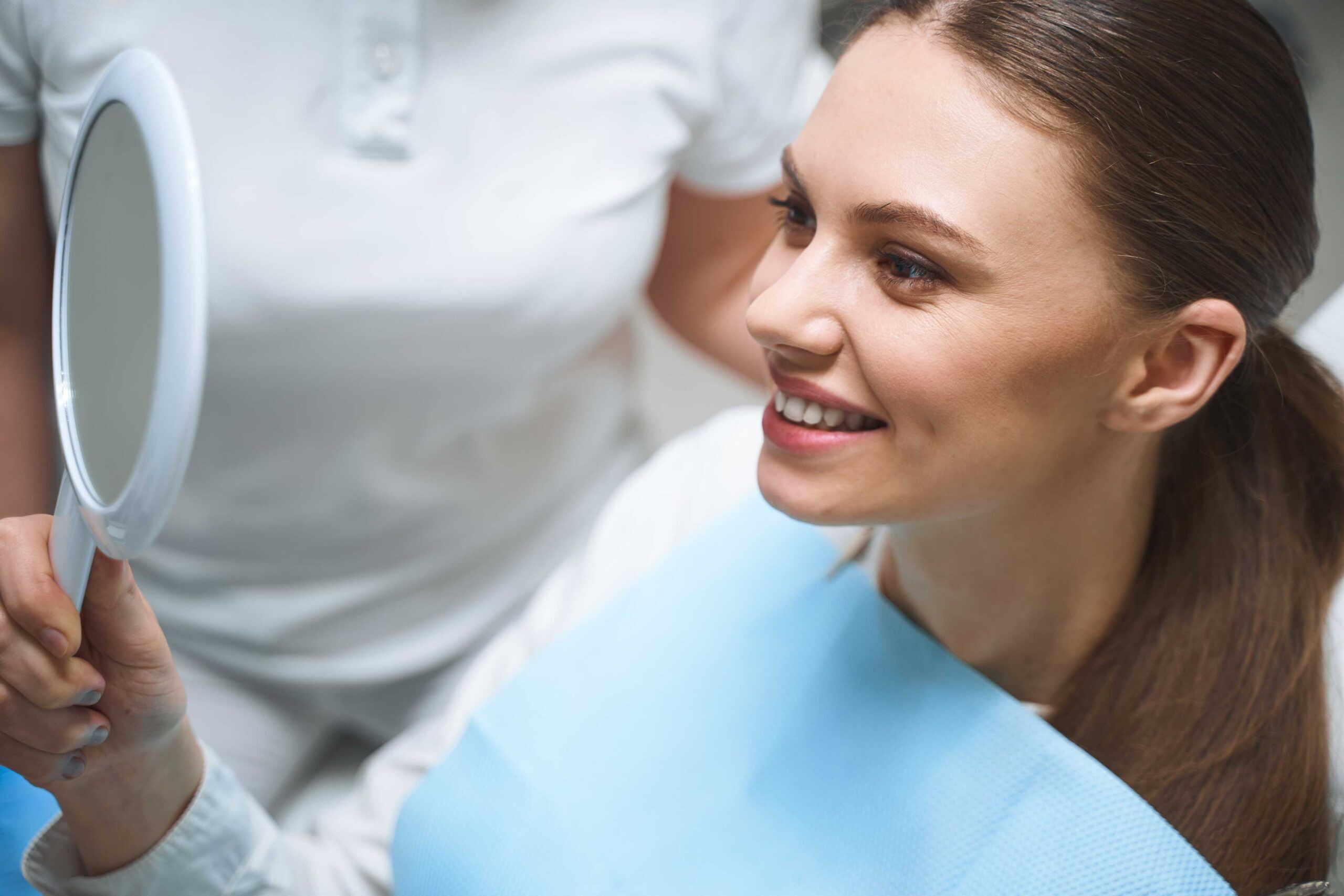Young woman looking in a mirror during dental treatment.