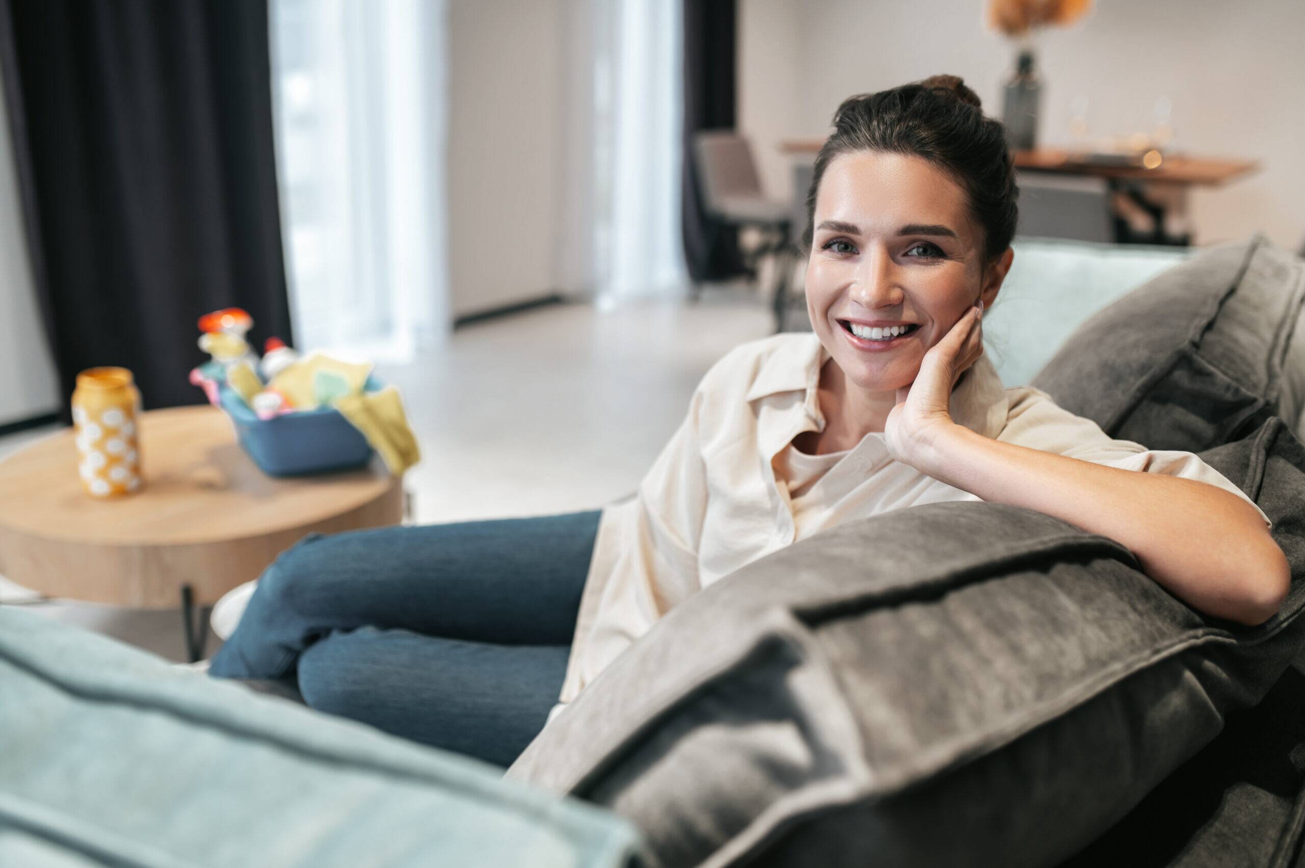Smiling young woman sitting at home on the sofa Smiling woman relaxing comfortably on a sofa at home