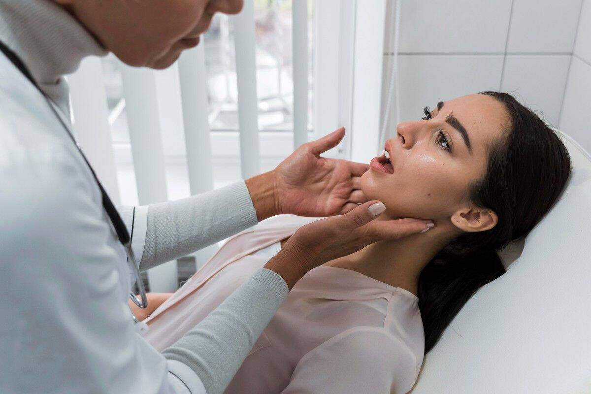 Dental Implants vs. Bridges Dentist examining a woman’s jaw during a dental checkup.